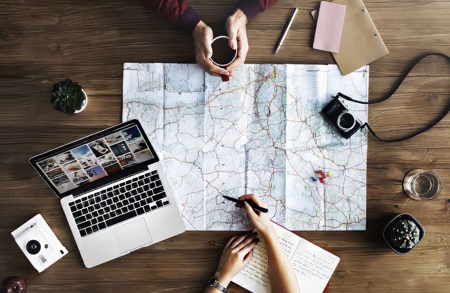 Travel advisor expert specializing in Guatemala and Belize, sitting at a desk with maps, a sample itinerary, and a camera laid out on the table, discussing travel plans with a traveler