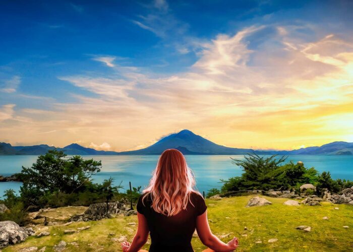 Woman meditating in a serene session at Lake Atitlan, surrounded by natural beauty, as part of the Guatemala Nature and Wellness Expedition