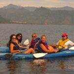 A group of women and a young man kayaking on the serene waters of Lake Atitlán, showcasing the safe and enjoyable travel experiences available in Guatemala.